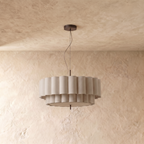 A Clérachic pendant light suspends a fluted double-tier fabric shade from a bronze ceiling canopy.