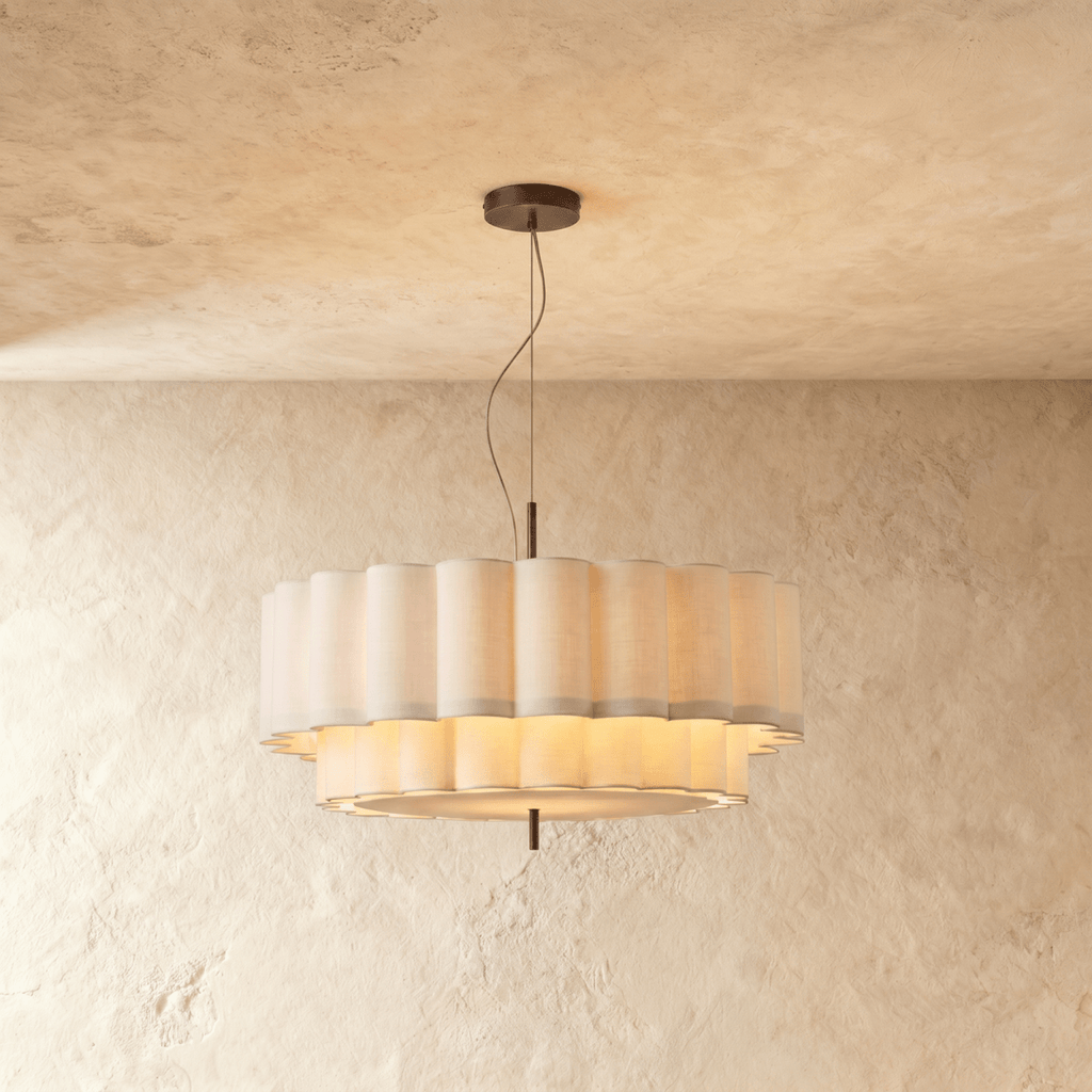 This Clérachic ceiling pendant glows warmly through its two-tier scalloped shade against a plaster backdrop.