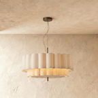 A Clérachic pendant light's ribbed fabric drum glows from within, its two tiers softly lit.