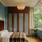This Clérachic ceiling pendant glows warmly above a bed, its scalloped shade set against mirrored wardrobe doors.