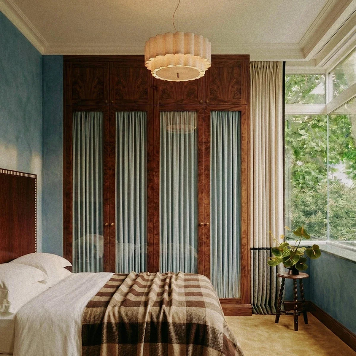 This Clérachic ceiling pendant glows warmly above a bed, its scalloped shade set against mirrored wardrobe doors.