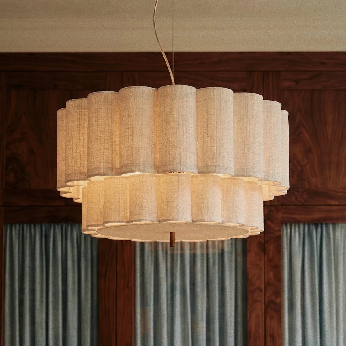A Clérachic pendant light glows warmly in a wood-paneled room, its fluted shade bright against dark walnut.