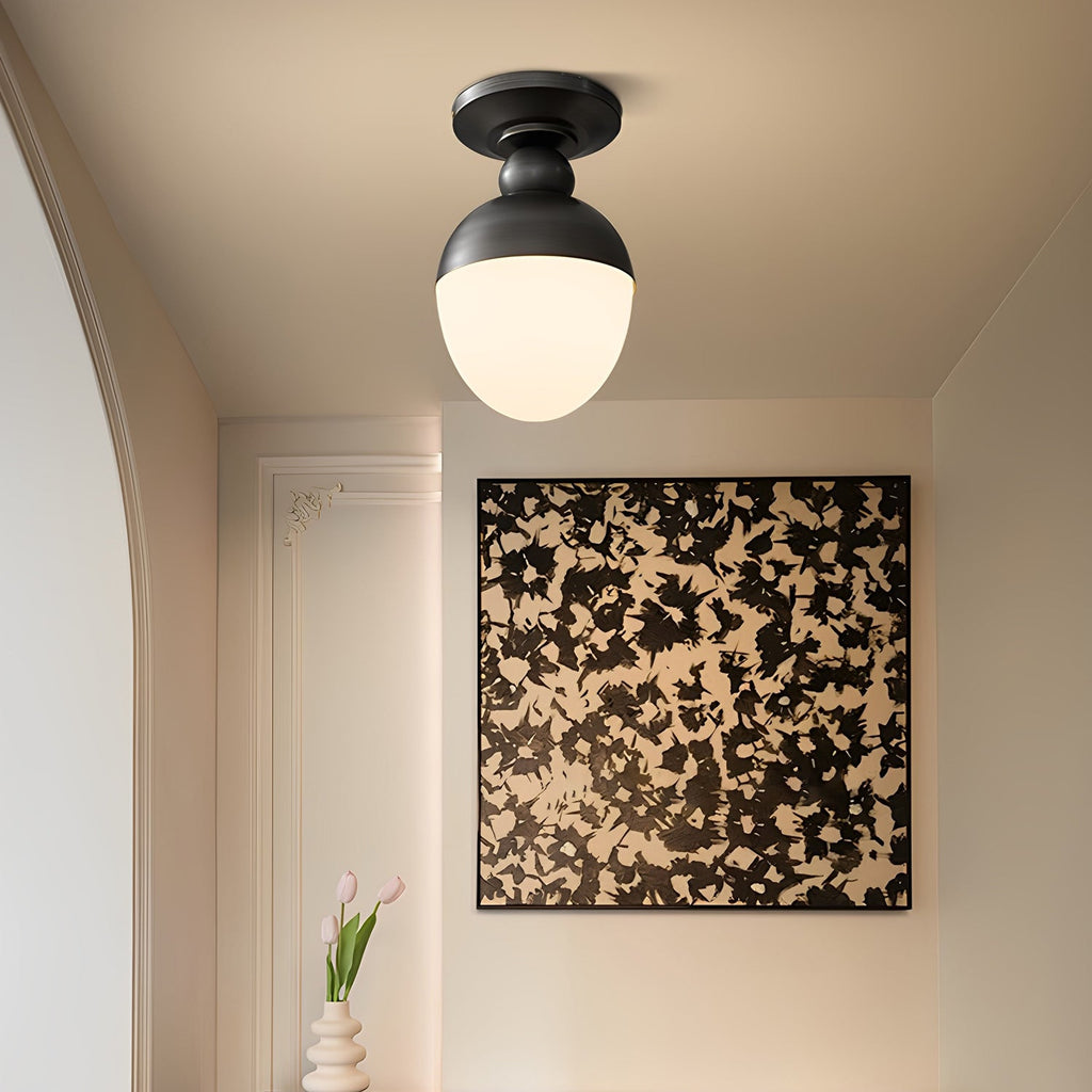 This Clérachic ceiling light has a black top and a glowing white globe, set in a cream room before a large black-and-white abstract artwork.