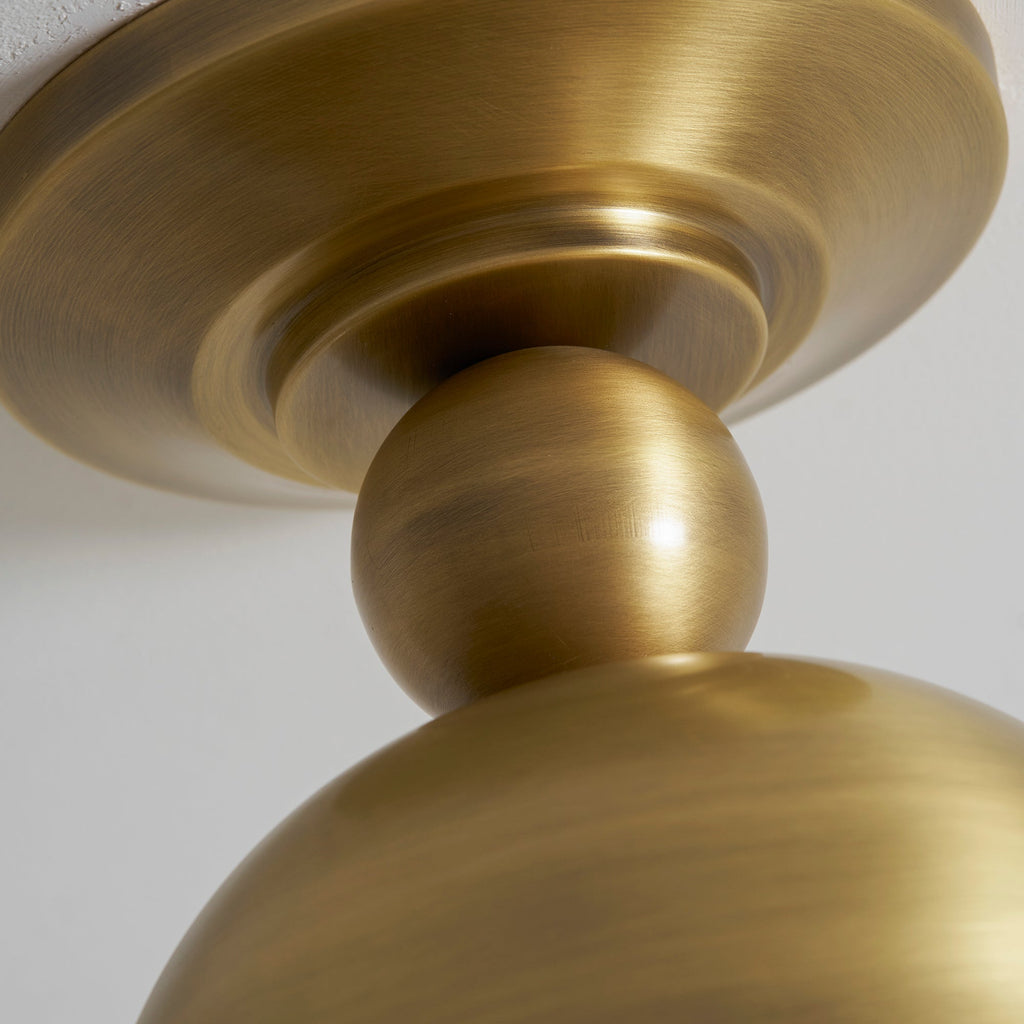 Close view of the brushed antique brass canopy and ball joint on this Clérachic ceiling light, with the top of the dome below.