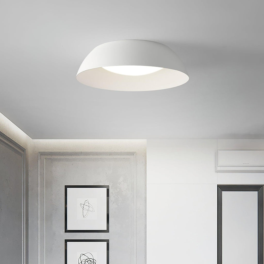 White low-profile dome ceiling light from Clérachic in a grey room with framed line drawings and a white wardrobe.