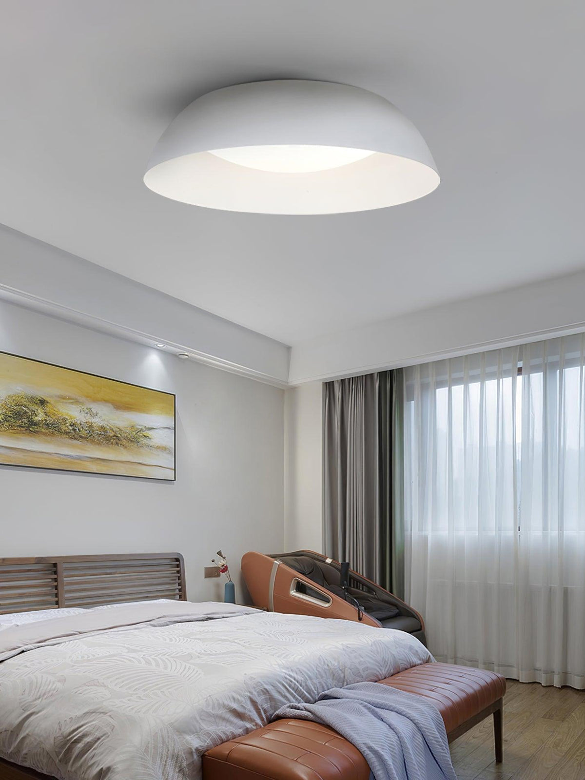 Low white dome ceiling light above a bedroom with a slatted bed, an orange bench and a painting, from Clérachic.