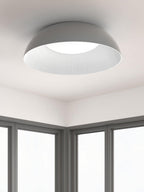 Grey outer shell and ribbed white inner rim of this Clérachic ceiling light, seen from below in a corner of a room with tall windows.