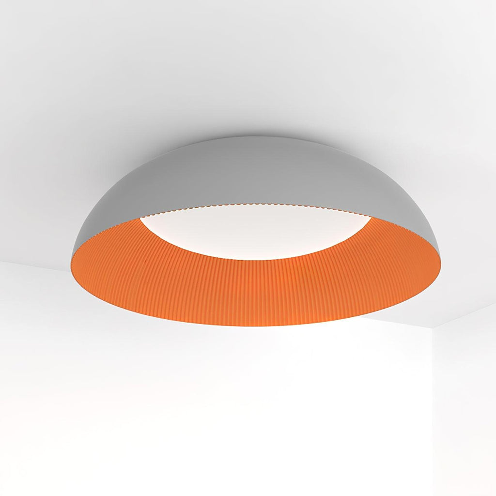Grey dome with a ribbed orange interior, this Clérachic ceiling light is seen from below with its white LED diffuser lit.