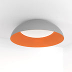 Grey dome with a ribbed orange interior, this Clérachic ceiling light is seen from below with its white LED diffuser lit.