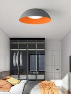 Grey dome with orange interior from Clérachic hung above a bedroom with a glass-fronted wardrobe and orange bedding.