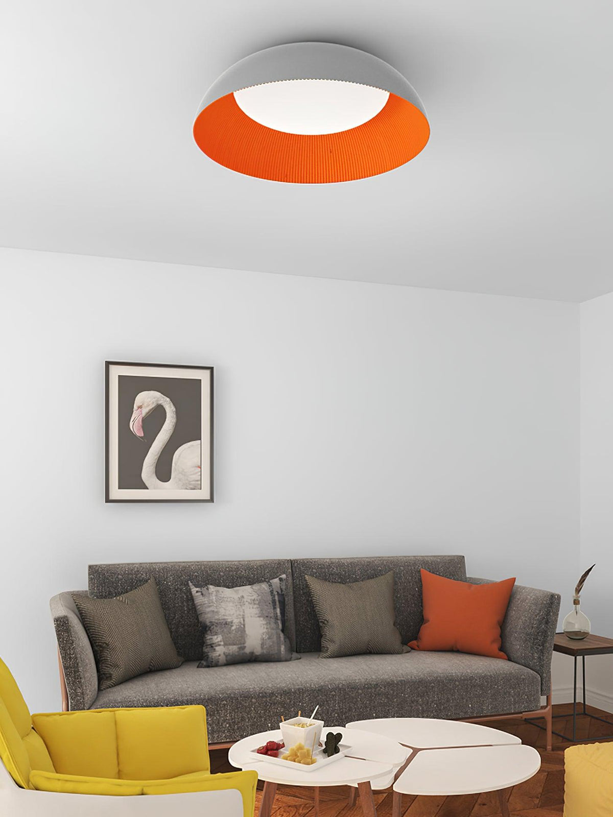 Grey and orange dome ceiling light from Clérachic over a living room with a grey sofa, a yellow chair and a flamingo print.
