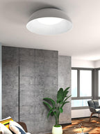 Low white dome ceiling light from Clérachic with a ribbed inner rim, over a room with a concrete-look wardrobe wall and a large leafy plant.