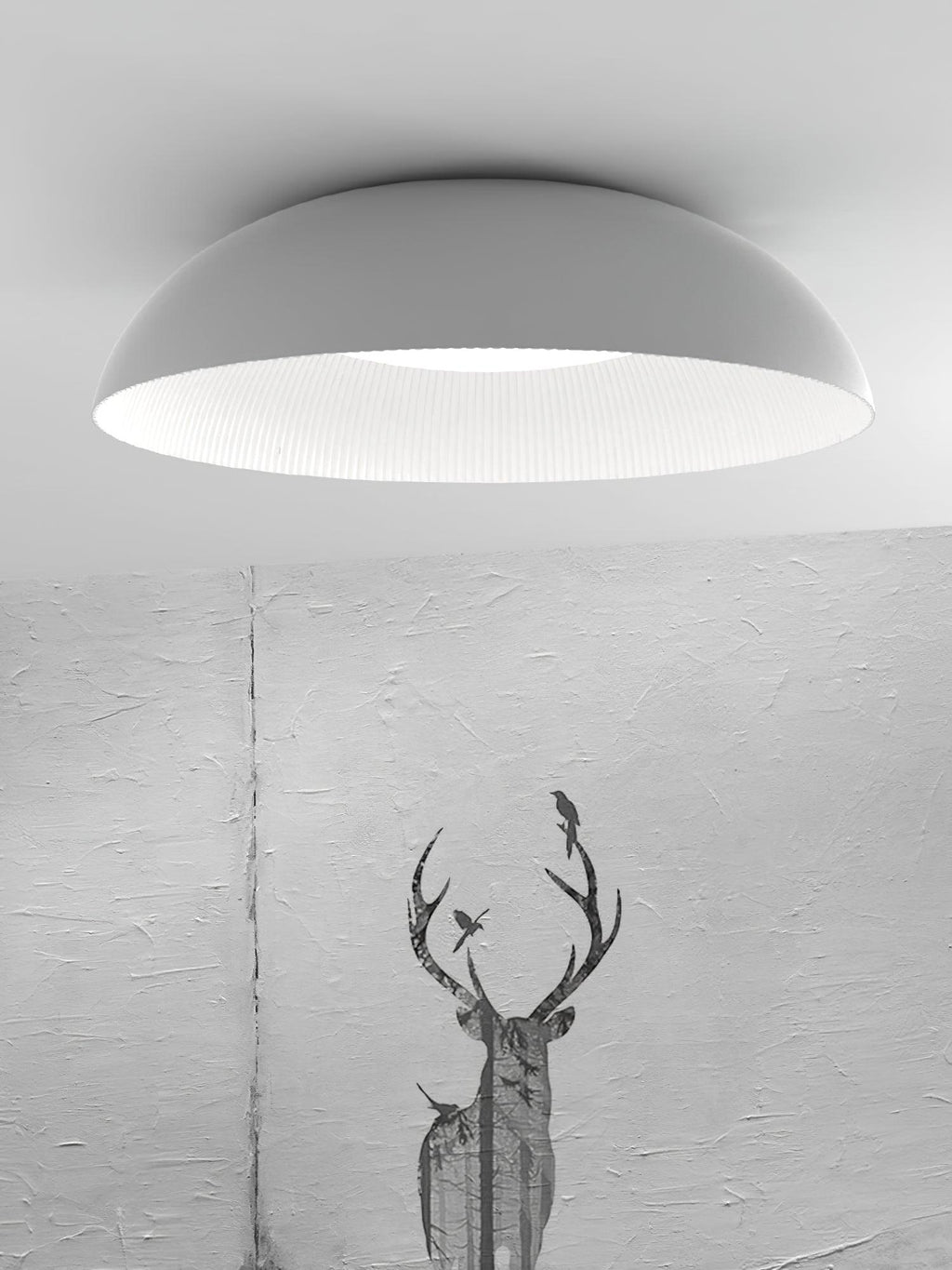 Wide white dome of this Clérachic ceiling light with its ribbed white interior, shown against a textured grey wall with a stag print.
