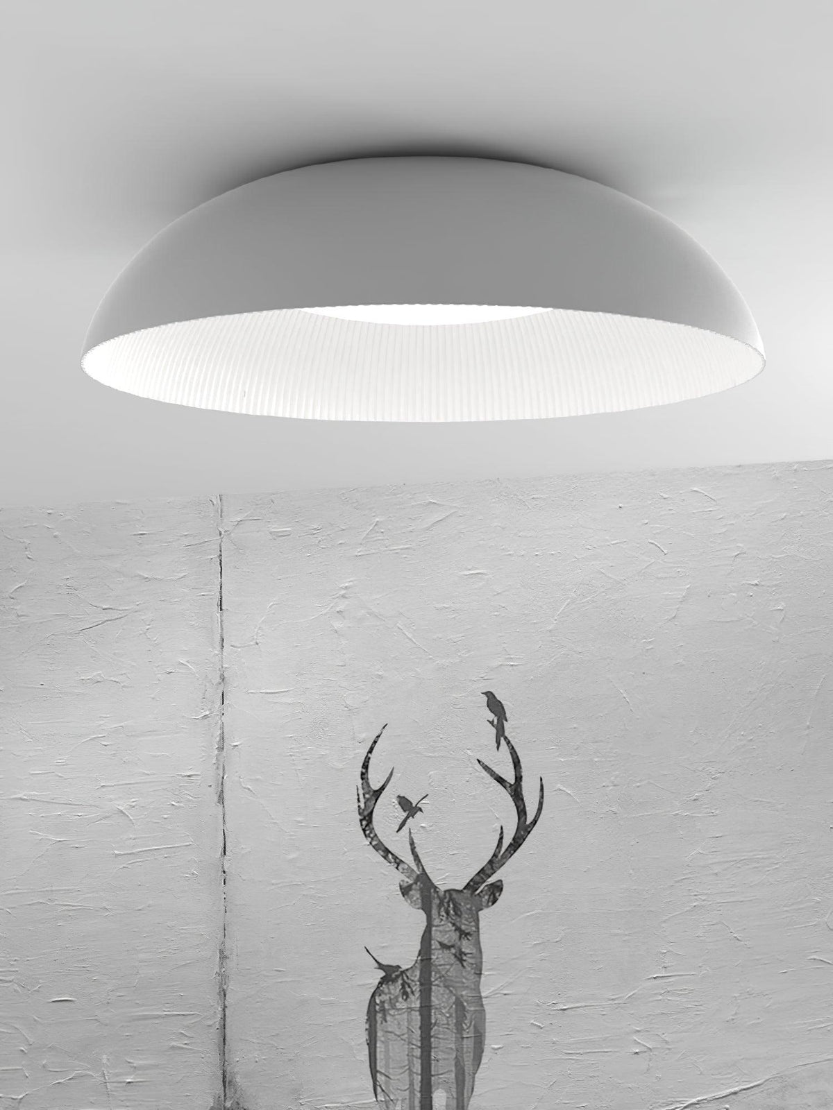 Wide white dome of this Clérachic ceiling light with its ribbed white interior, shown against a textured grey wall with a stag print.