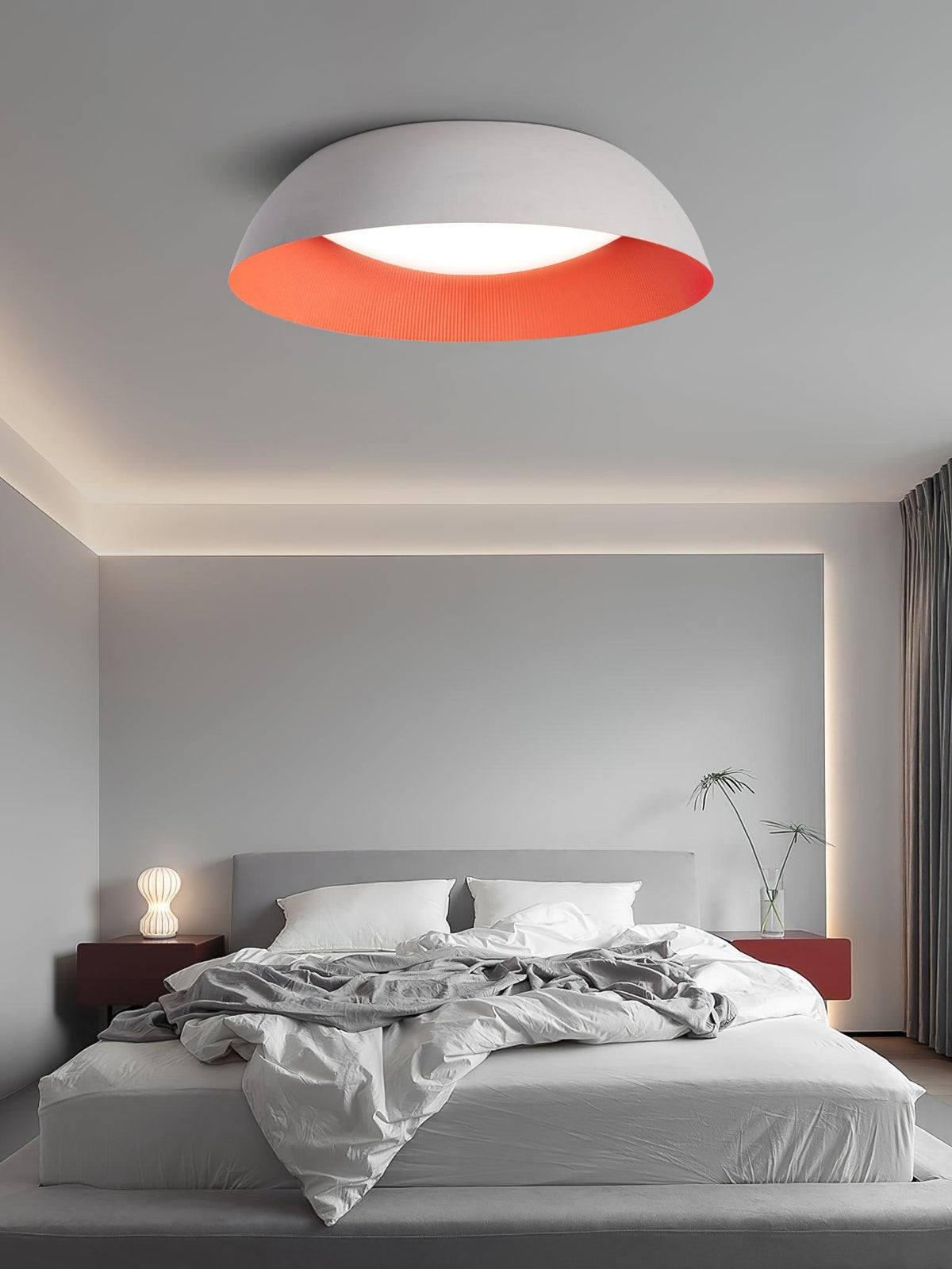 White dome with an orange interior above a low grey bed with a glowing bedside lamp, a Clérachic ceiling light in a calm bedroom.