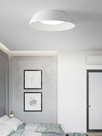 White dome ceiling light from Clérachic in a pale grey bedroom with panelled walls and two framed line drawings.