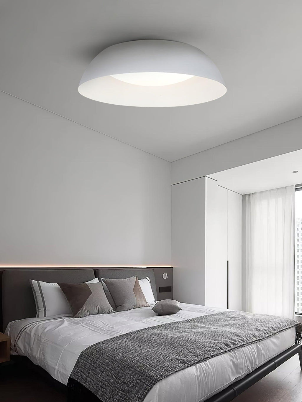 White dome ceiling light from Clérachic above a bed with a grey throw, with a dark headboard and sheer curtains.