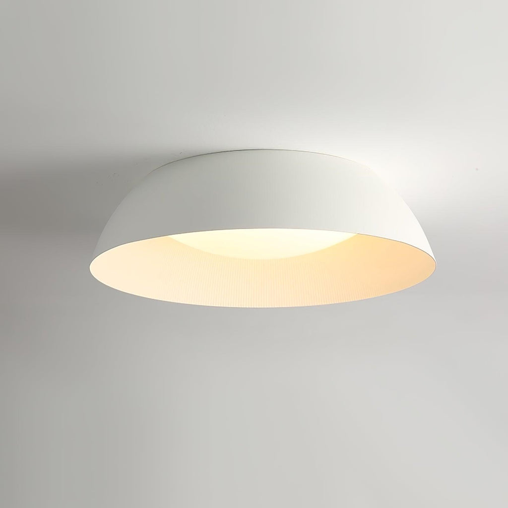 White dome ceiling light from Clérachic lit softly, its inner rim glowing cream, photographed from below.
