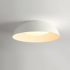 White dome ceiling light from Clérachic lit softly, its inner rim glowing cream, photographed from below.