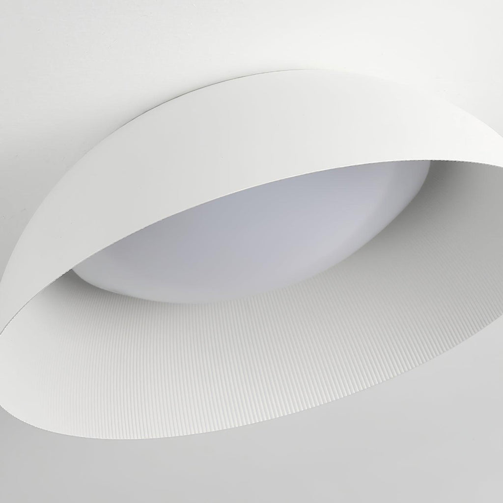 Close view of the white outer edge, ribbed interior and curved diffuser of this Clérachic ceiling light, seen from below.