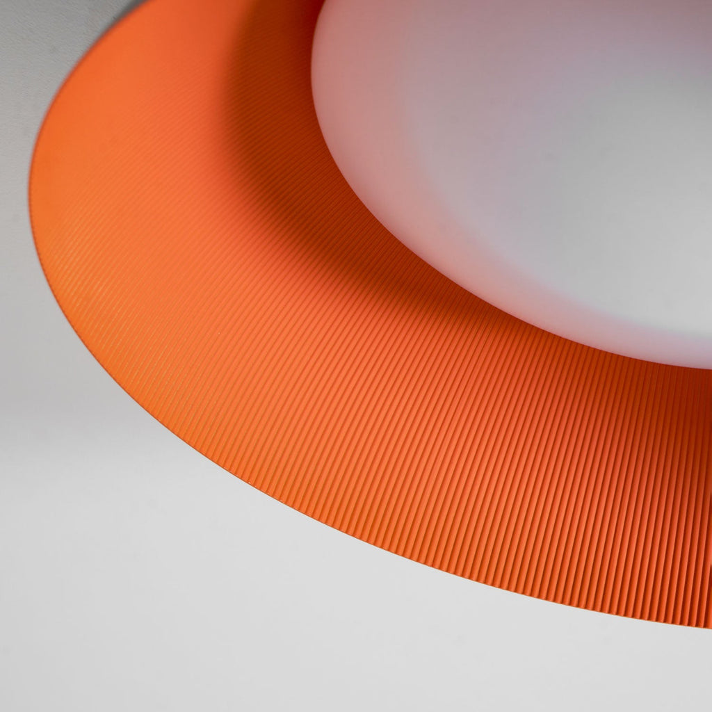 Close view of the finely ribbed orange interior and white diffuser of this Clérachic grey and orange ceiling light.