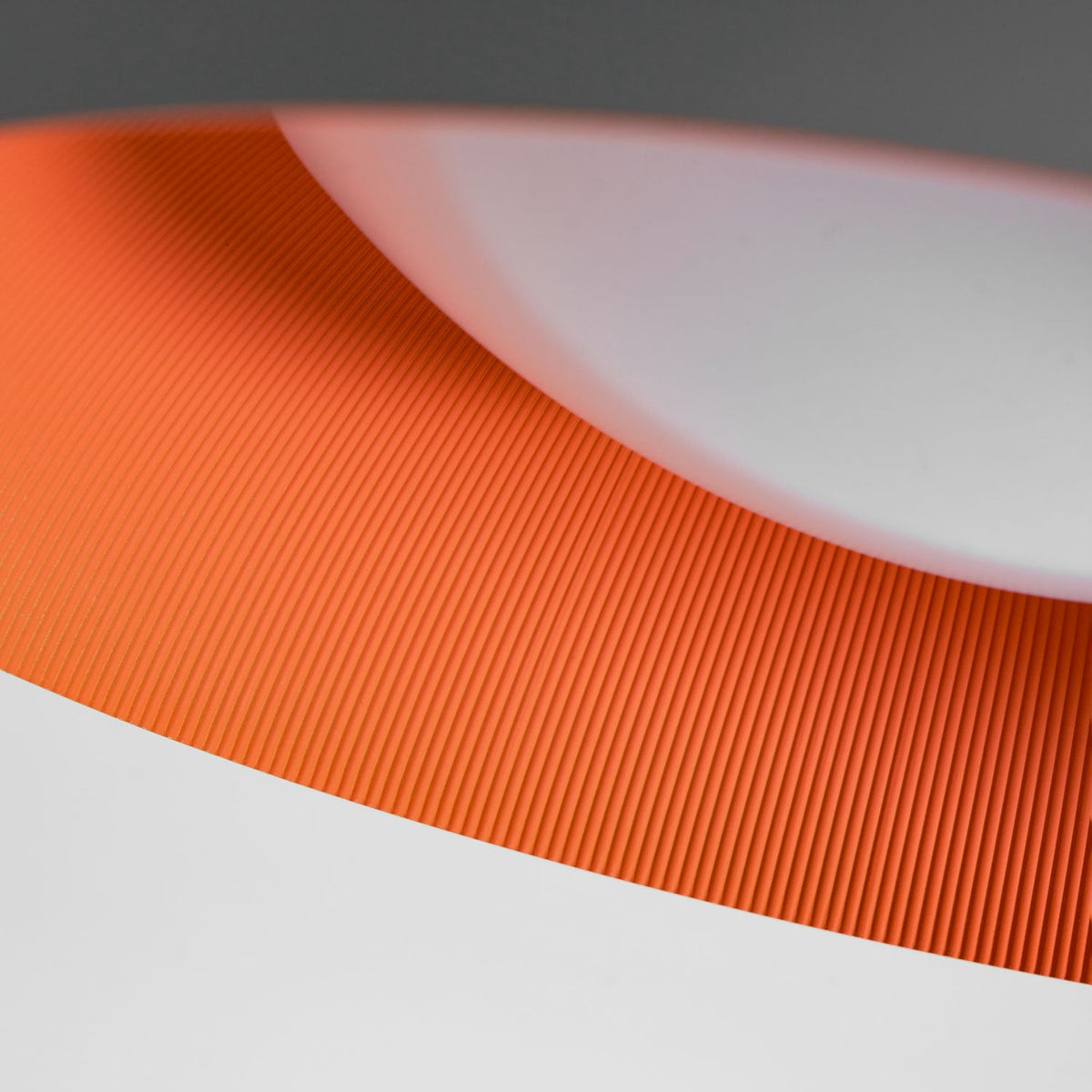 Close view of the grey rim, ribbed orange inside and white diffuser on this Clérachic ceiling light.
