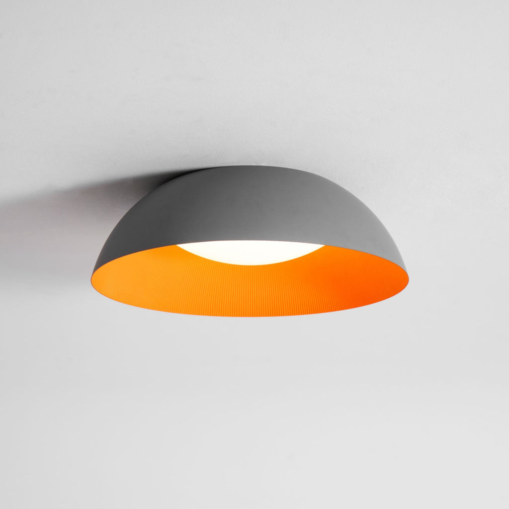 Grey dome with a bright orange interior and a white diffuser, this Clérachic ceiling light is seen from slightly below.