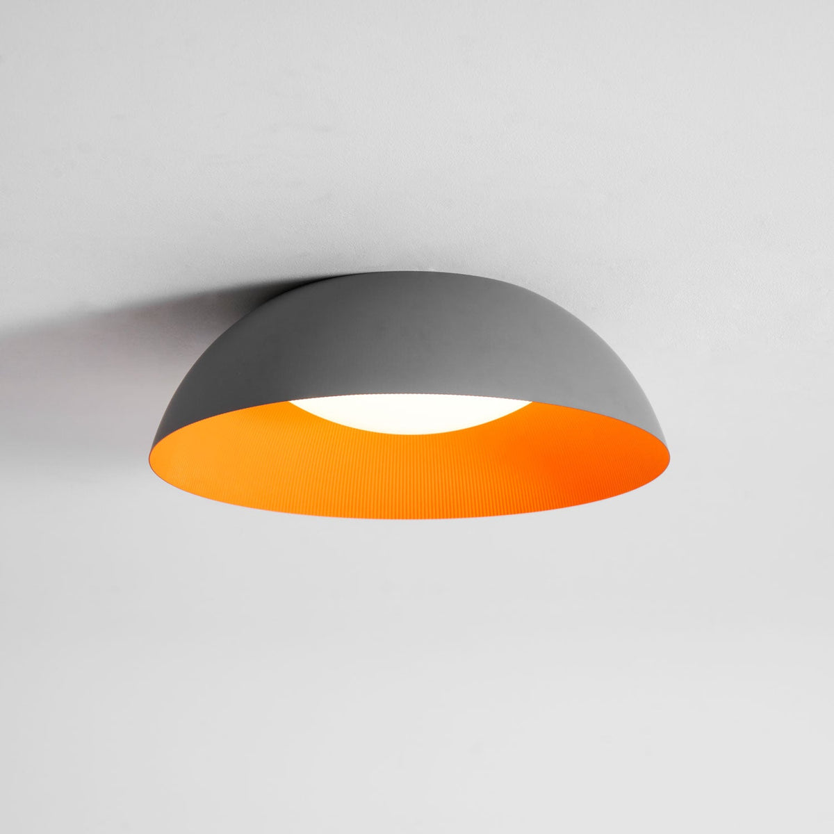 Grey dome with a bright orange interior and a white diffuser, this Clérachic ceiling light is seen from slightly below.
