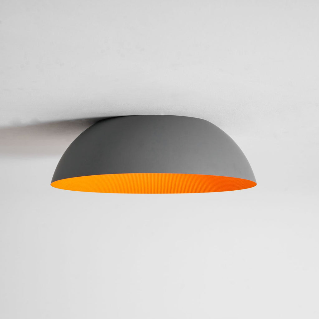 Side-on view of the grey dome of this Clérachic ceiling light with a narrow strip of orange showing under the rim.
