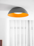 Closer view of the grey dome and glowing orange interior of this Clérachic ceiling light, with sheer curtains behind.