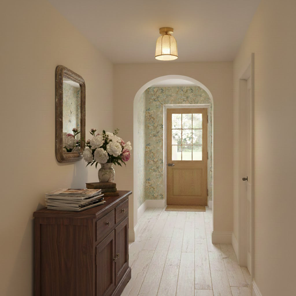 This Clérachic ceiling light glows in a hallway with cream walls, a dark wood chest, a vase of flowers and an arched opening to a door.