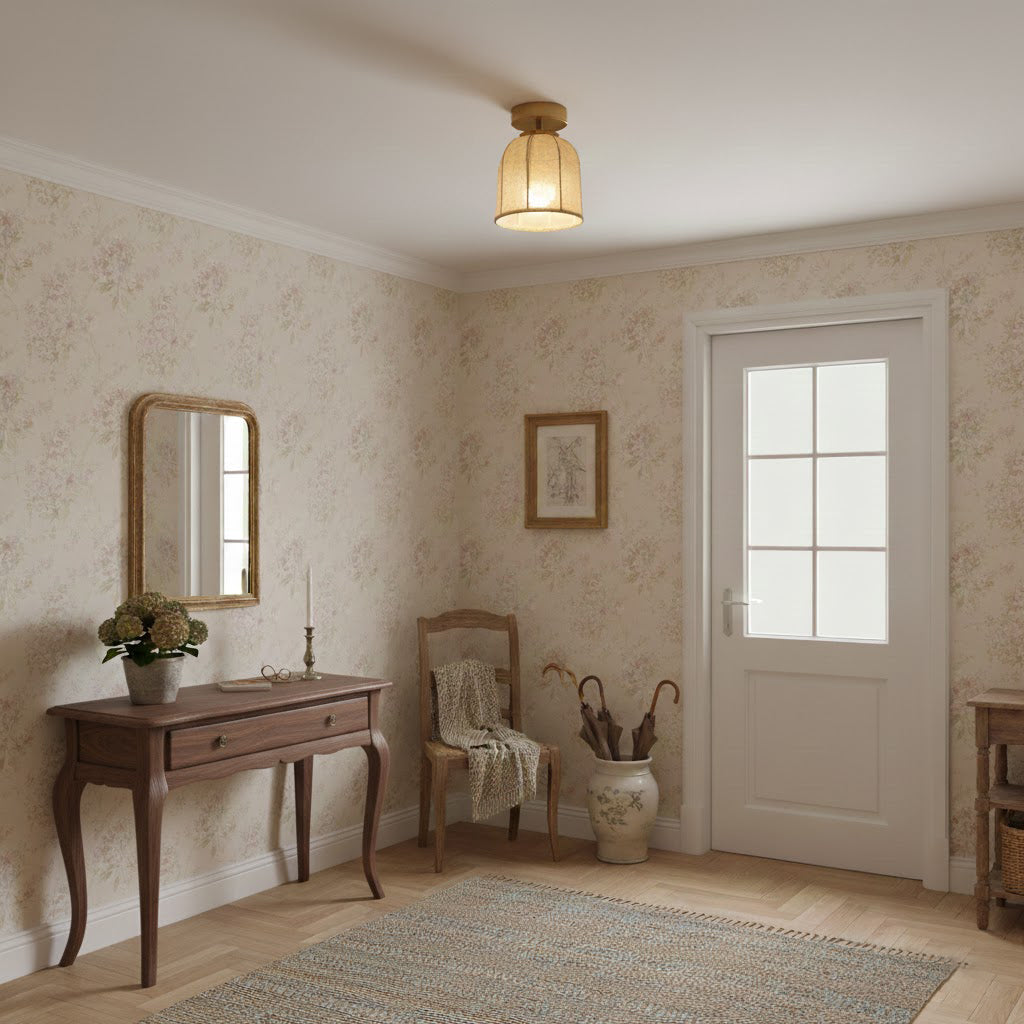 A small Clérachic flush-mount light with a linen shade hangs in an entrance room with floral wallpaper, a console table and a white door.
