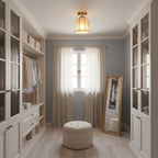 Clérachic linen-shade ceiling light in a walk-in wardrobe with glass-fronted cupboards, a round pouffe and a tall mirror by a curtained window.