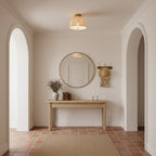 Clérachic flush-mount light with a linen shade, hung in an entrance with two arches, a round mirror and a pale wooden console.