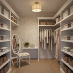 A wider Clérachic linen-shade ceiling light above a dressing area with open shelves, hanging clothes, baskets and a small floral stool.