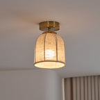 A Clérachic flush-mount light with a lit linen shade and gold canopy, seen from slightly below against a soft grey ceiling.