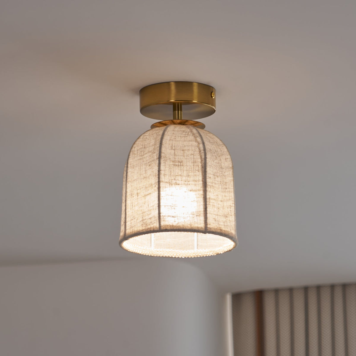 This Clérachic ceiling light on a cooler setting, its linen shade glowing pale beside a striped curtain.