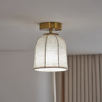 Clérachic ceiling light lit with a cool white glow through the linen shade, with a striped curtain behind and a gold canopy above.