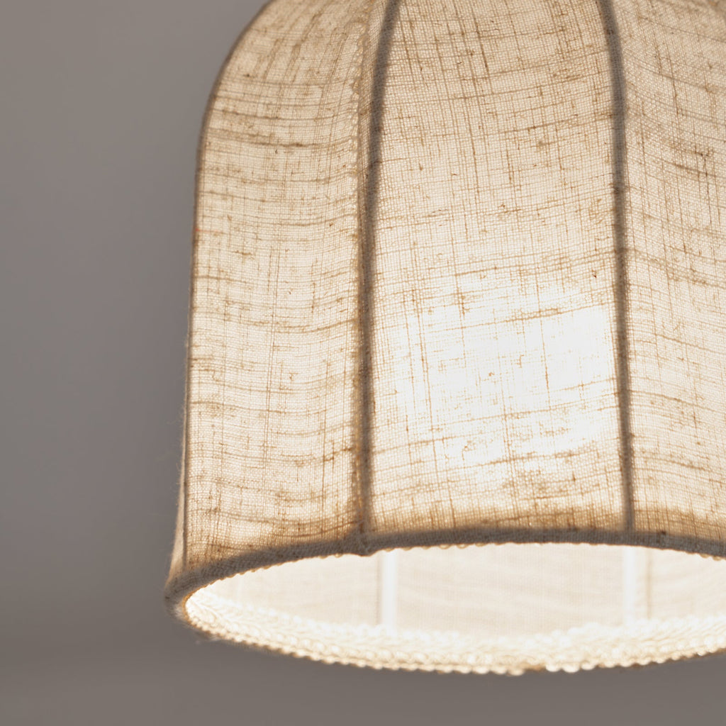 Close view of the pale linen weave, the ribs and the beaded edge on this Clérachic ceiling light with a cooler glow.