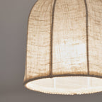 Close view of the pale linen weave, the ribs and the beaded edge on this Clérachic ceiling light with a cooler glow.