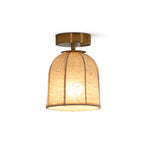 A lit Clérachic flush-mount light on a white backdrop, its ribbed linen shade glowing amber under a gold canopy.