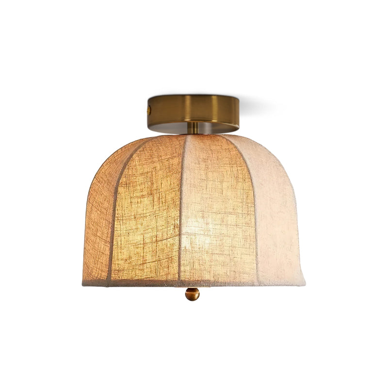 Clérachic wide flush-mount ceiling light with panelled linen shade lit from within, a gold canopy above and a small gold bead beneath.