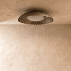 Clérachic ceiling light in vintage brass viewed from another angle, its slotted rim glowing softly overhead.
