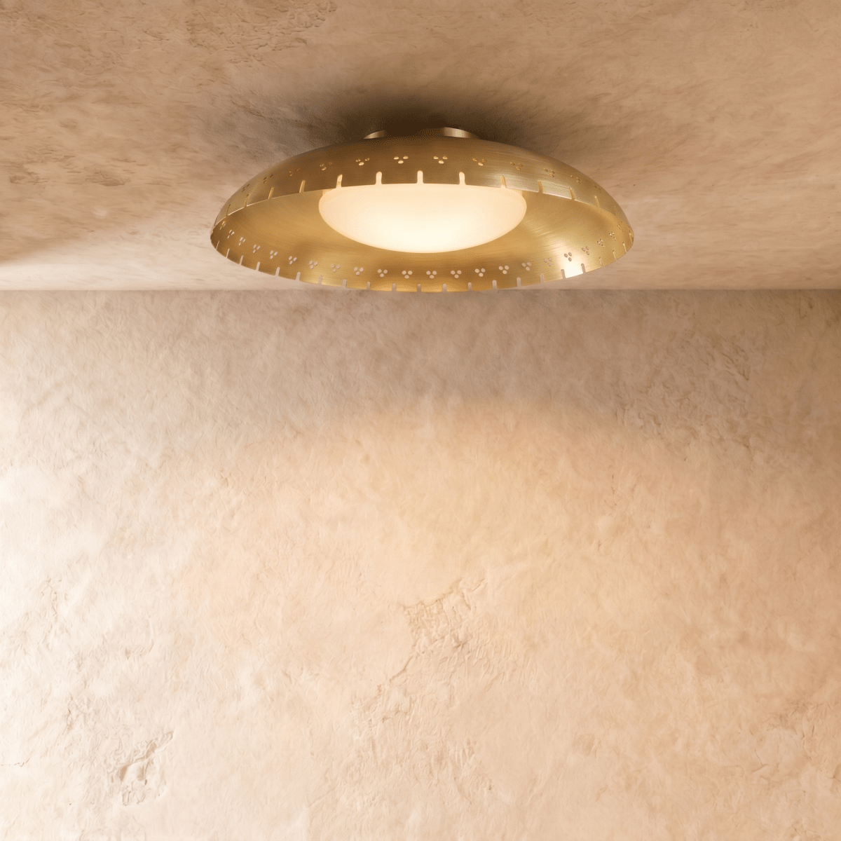 Clérachic ceiling light in brushed brass, the perforated drum shade casting a warm halo on the ceiling.