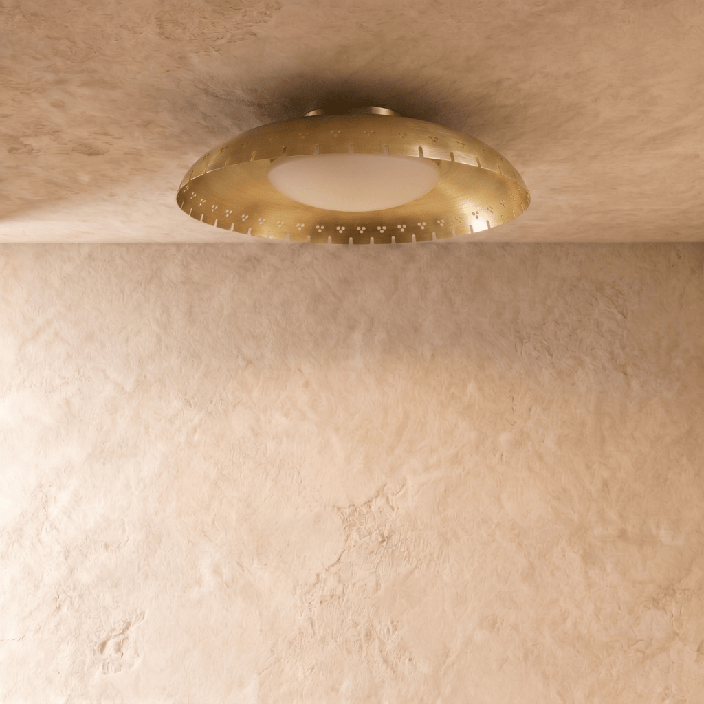 Clérachic ceiling light in brushed brass shown close, the frosted glass diffuser glowing beneath the rim.