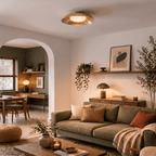 Clérachic ceiling light in brushed brass glowing above a living room with a sofa, plants and an archway nook.