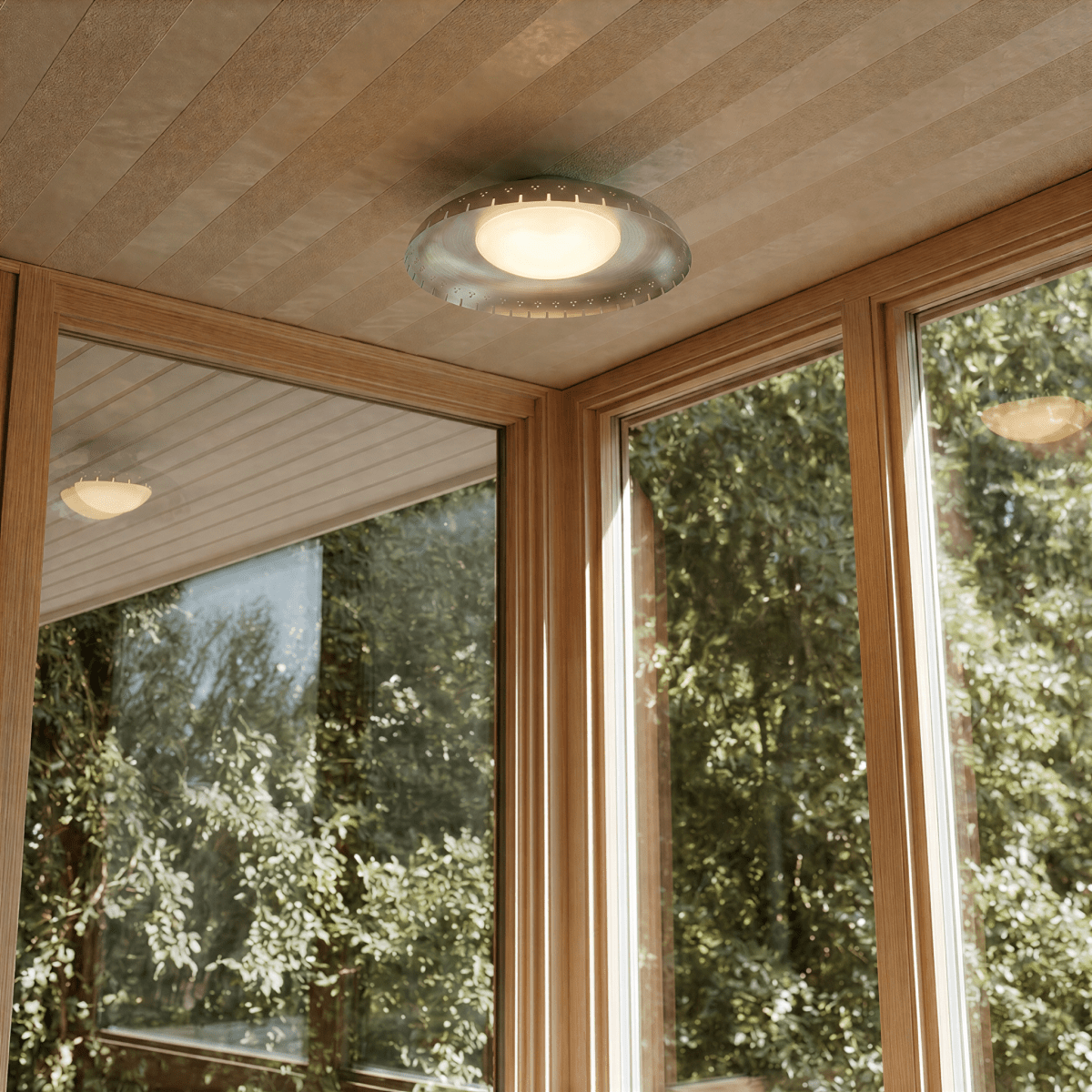 Clérachic ceiling light in chrome mounted in a wood-paneled sunroom overlooking a leafy garden view.