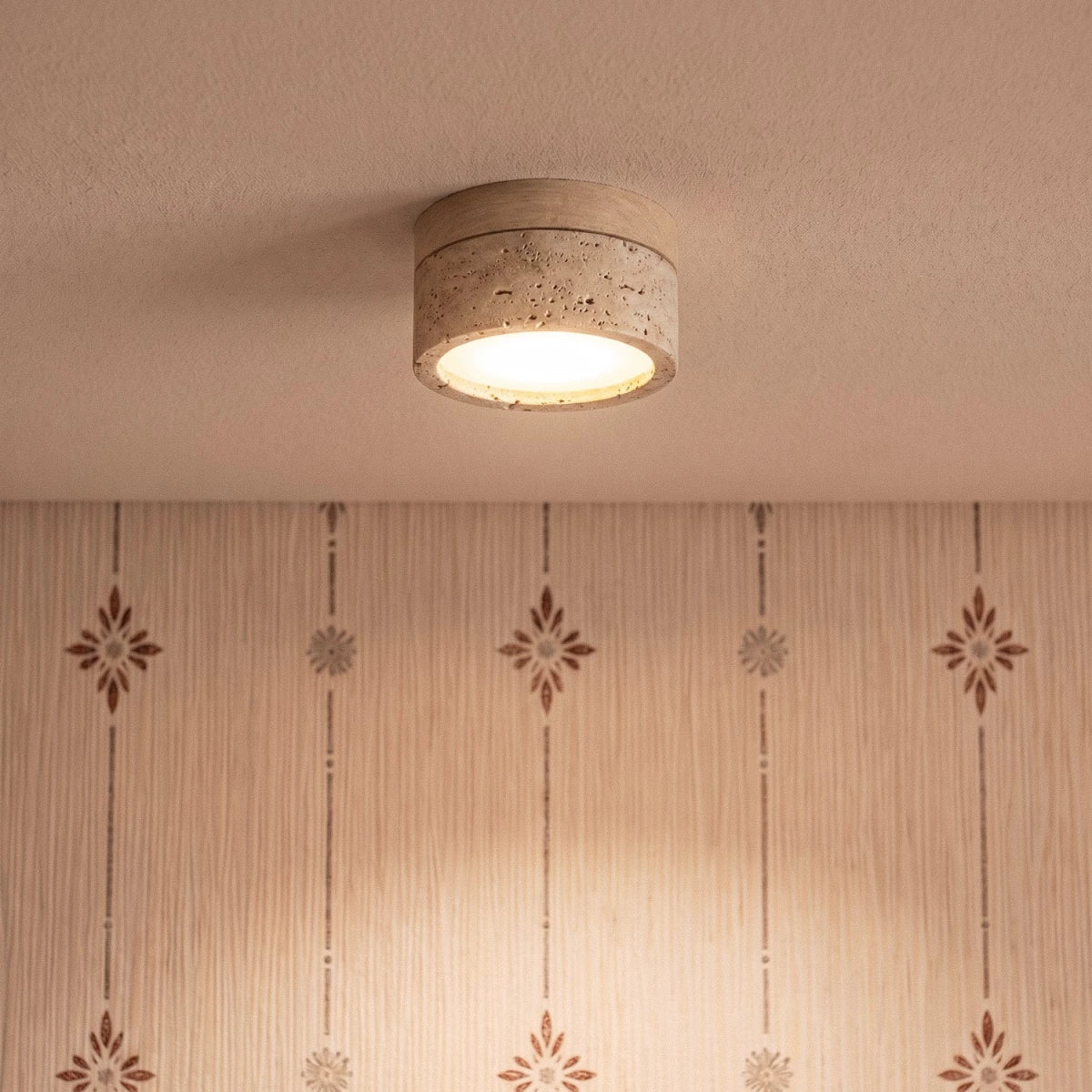 Clérachic ceiling light in light wood glowing above a wallpapered room, a closer view of the fixture.