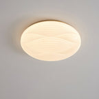 Looking up at this Clérachic ceiling light, its gold rim and wavy ribbed shade lit softly against a grey ceiling.