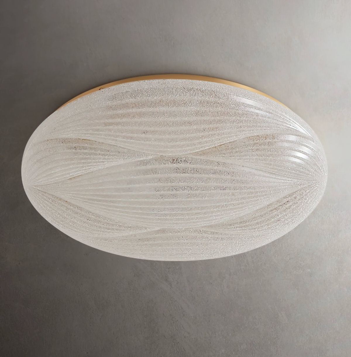 A textured translucent shade with fine wave ribs and a gold rim, on this unlit Clérachic ceiling light against a dark grey wall.